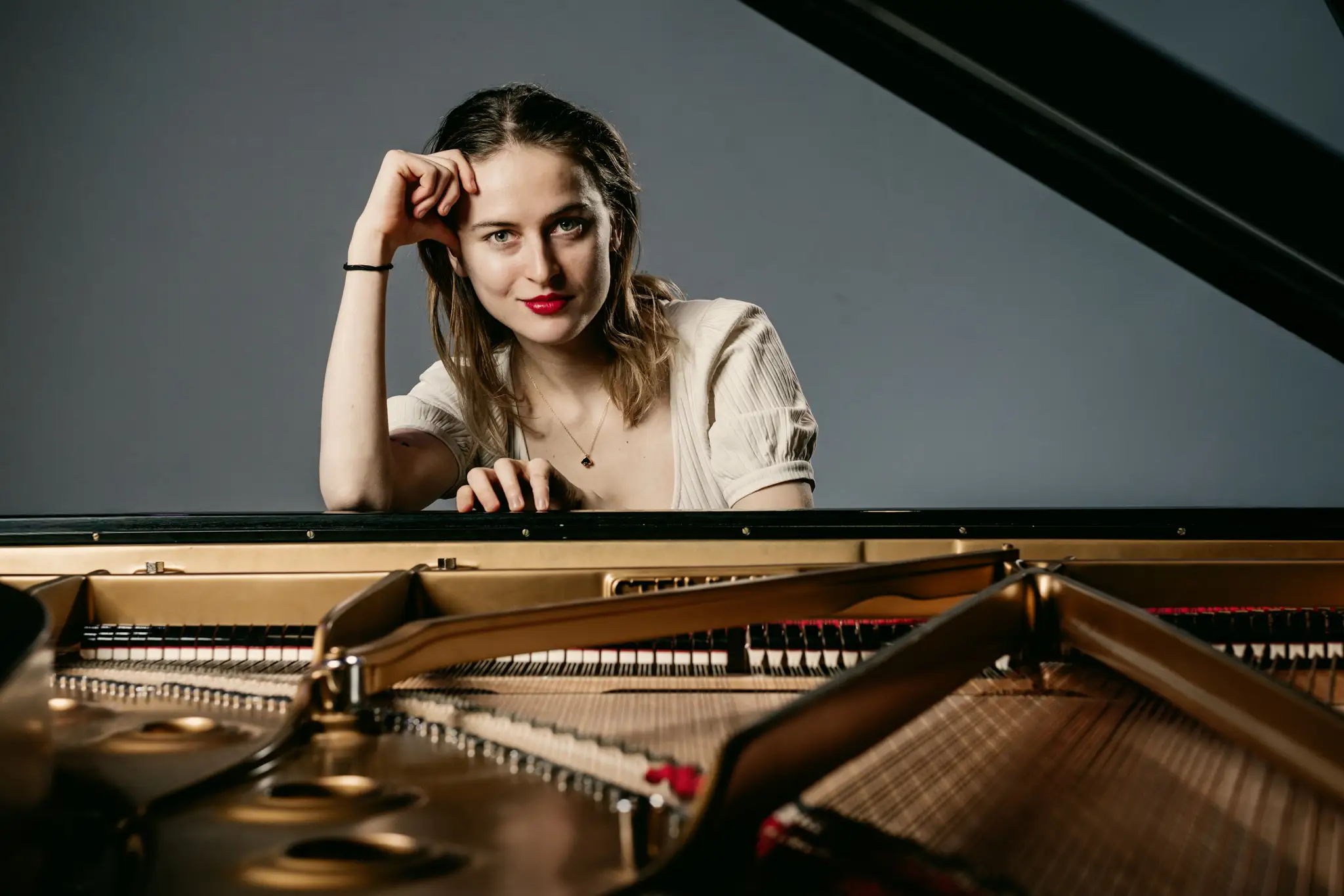 Musikerin Portrait Eve Kerloc’h Piano Maastricht Ausdrucksstarkes Portrait für Musik und Bühne – Pianistin entspannt am Instrument, durch Flügelklappe aufgenommen.