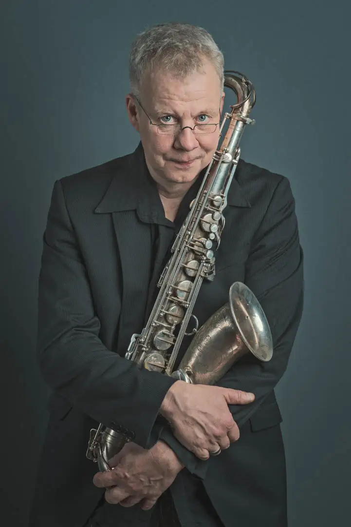 Musikerportrait Aachen Claudius Valk Saxophone Künstlerportrait für Musik und Bühne – Saxophonist mit dunklem Hintergrund und direktem Blick.