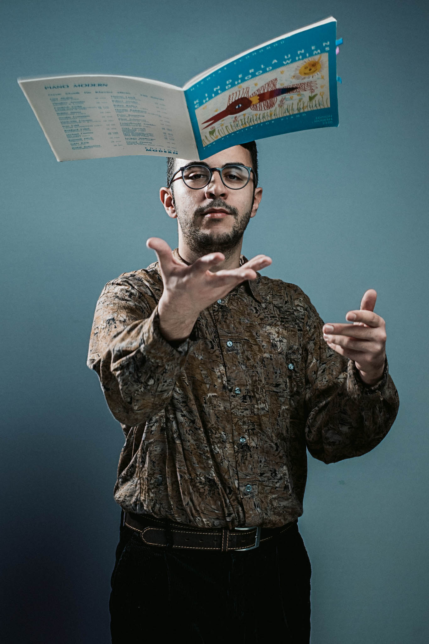 Vasileios Gavvaris – Portraits Kreatives Porträt eines Musikers. Er wirft ein offenes Notenheft in die Höhe - der Moment wird eingefangen